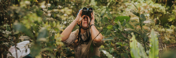 Hana Weaver in the jungle looking through binoculars