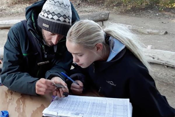 researcher shows a student how to band a songbird