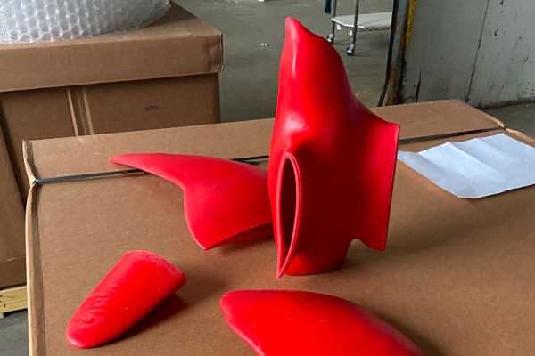 Red 3D prints of four pieces that together form a stylized Peregrine Falcon sitting on a table.