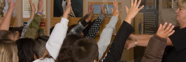 Students raise their hands in a class taught by Volunteer Marcia Franklin 