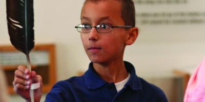 A school boy examines a feather