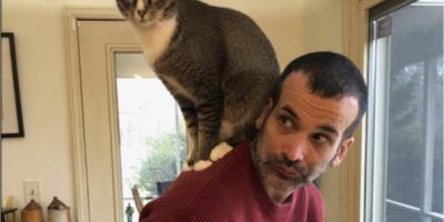 A man with a cat sitting on his shoulder